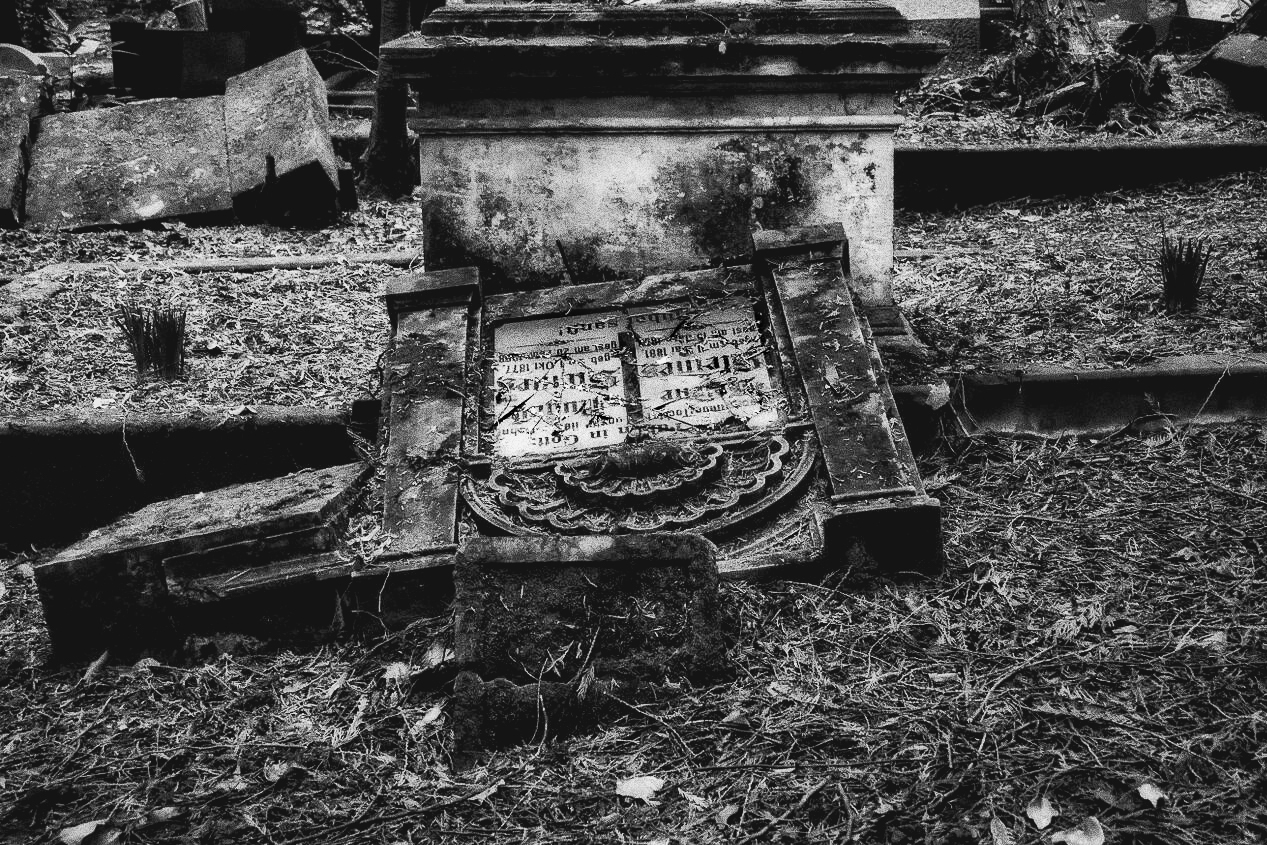 Schwarzweißaufnahme eines alten, umgestürzten Grabsteins auf dem Alten Friedhof Saarbrücken