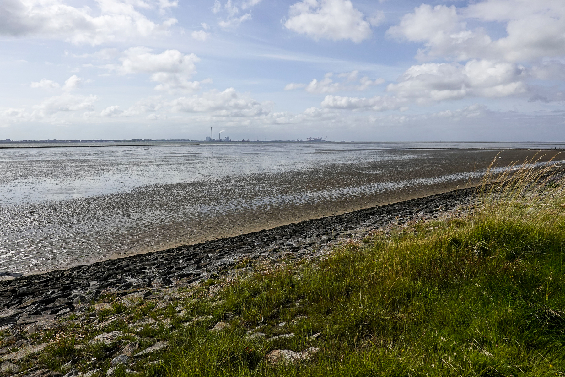 Wattfläche bei Butjadingen mit sichtbaren Schlammstrukturen, flachem Wasser und weitem Himmel, fotografiert an der Nordseeküste