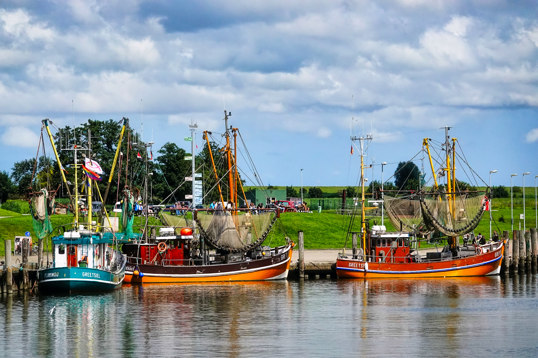 Fischerboote im Hafen von Greetsiel, mit Fischernetzen, Masten und ruhigem Wasser im Vordergrund, typischer Nordsee-Kutterhafen