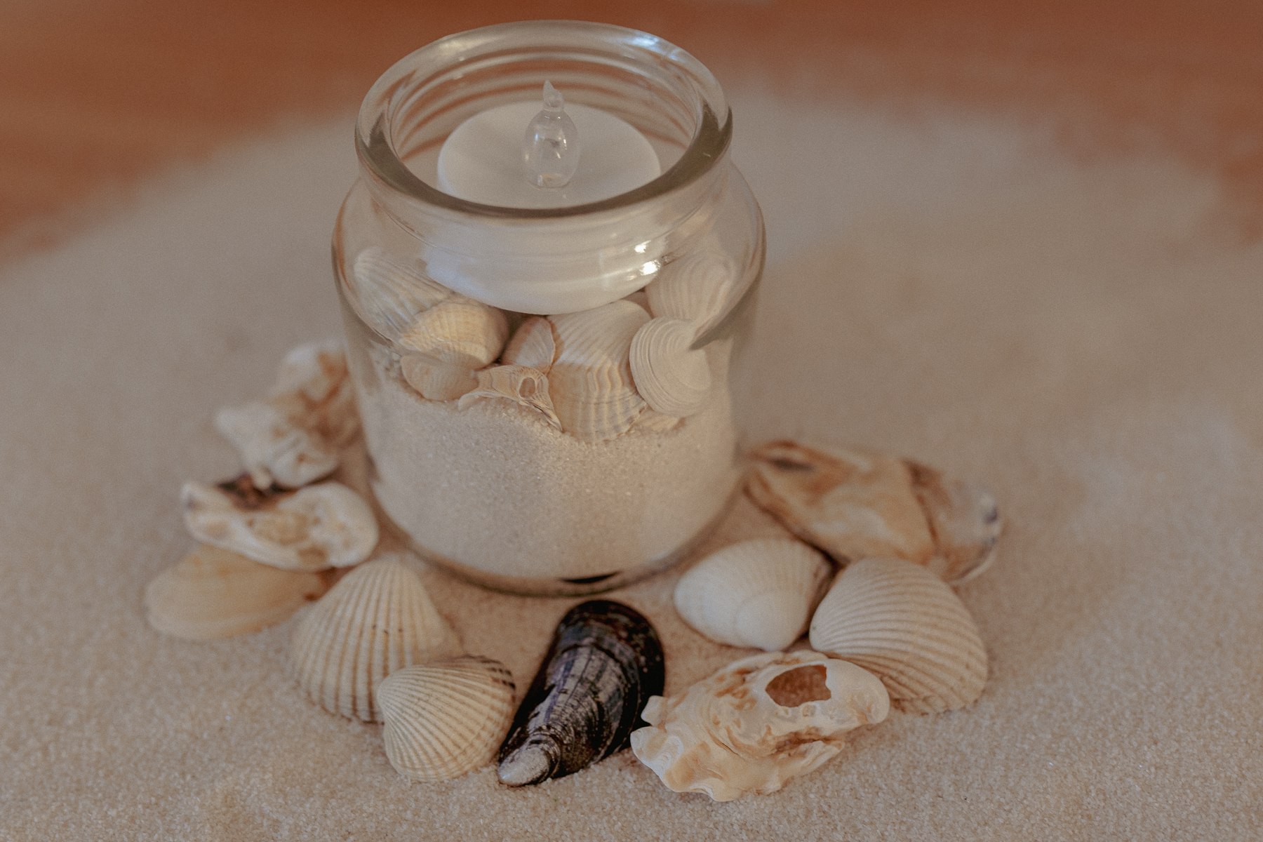Glas mit Nordseesand und Muscheln als Urlaubssouvenir, zuhause arrangiert